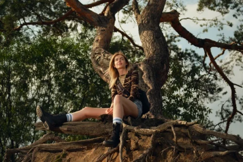 Femme assise sur des racines d'arbre, connexion à la nature