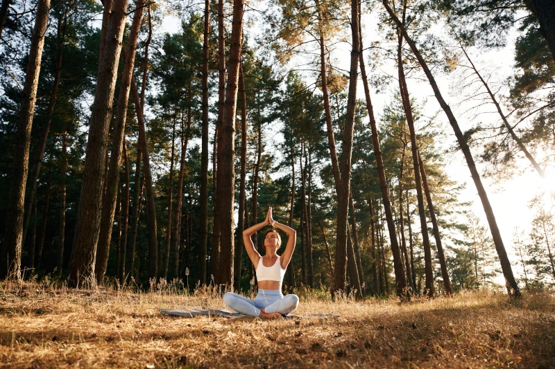 Une femme pratique la meditation pleine conscience dans la forêt